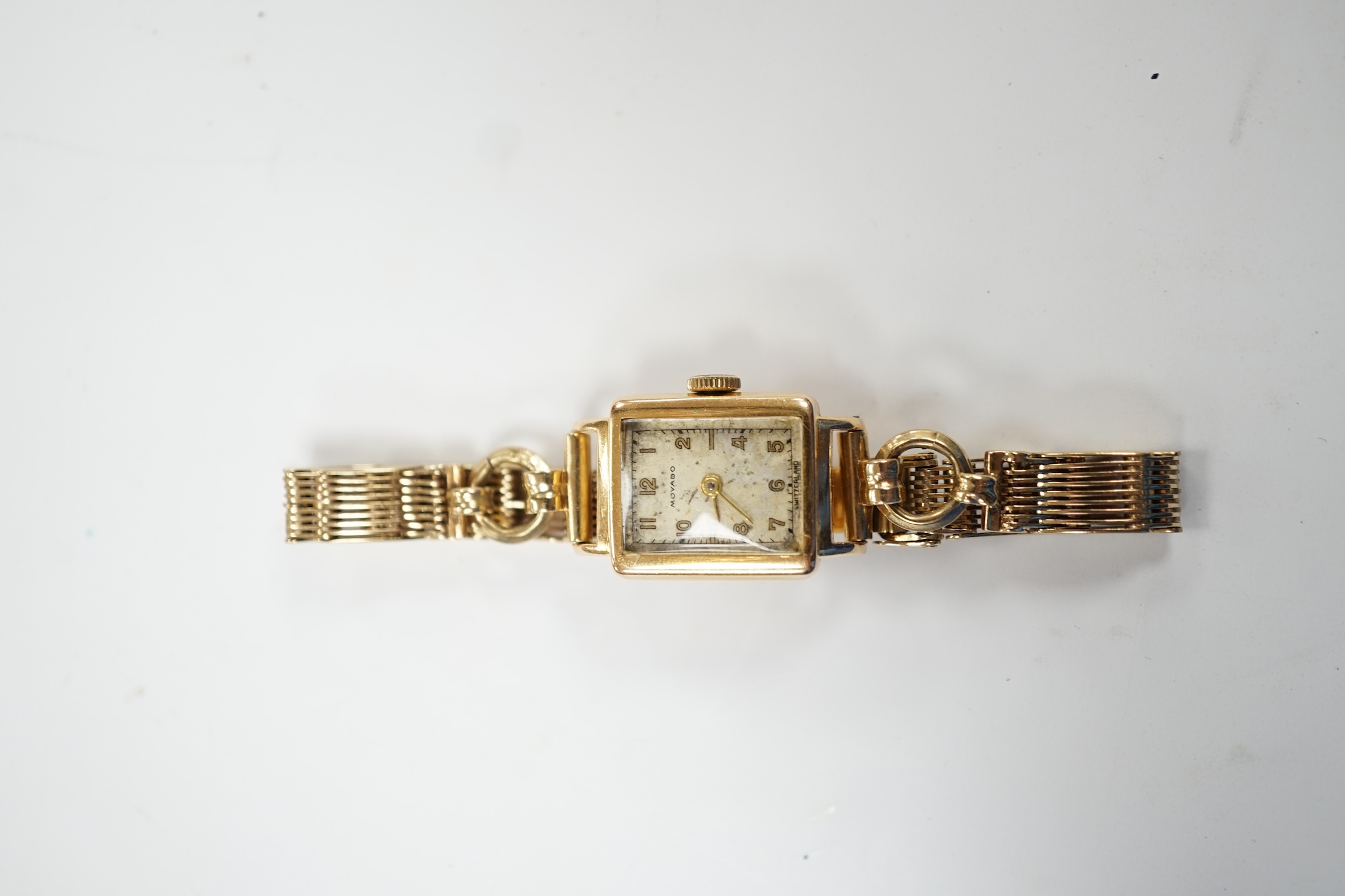 A lady's 18ct gold Movado manual wind wrist watch, on a 9ct gold bracelet. Fair condition